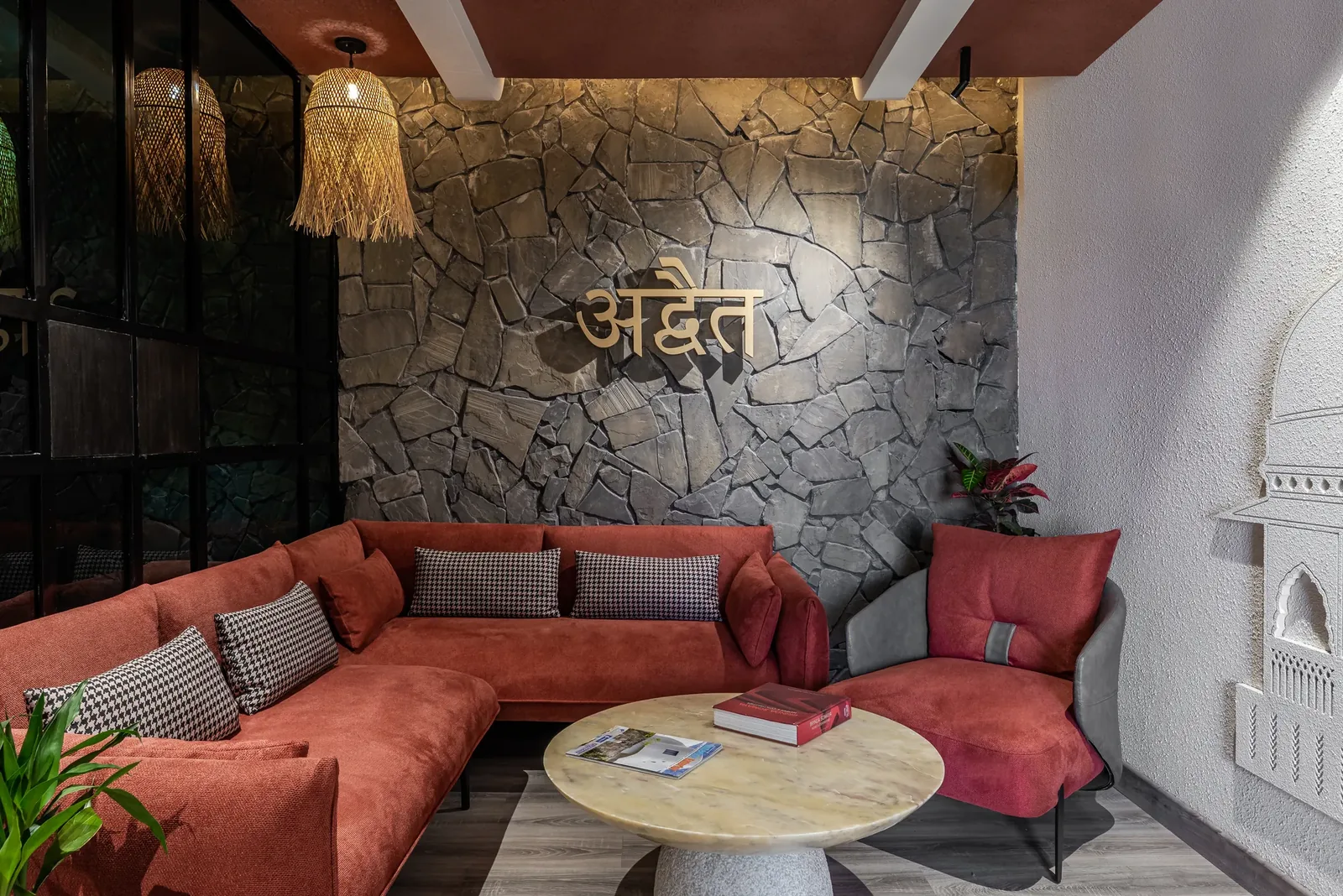 ADVAIT studio lounge, stone wall with brass अद्वैत lettering
